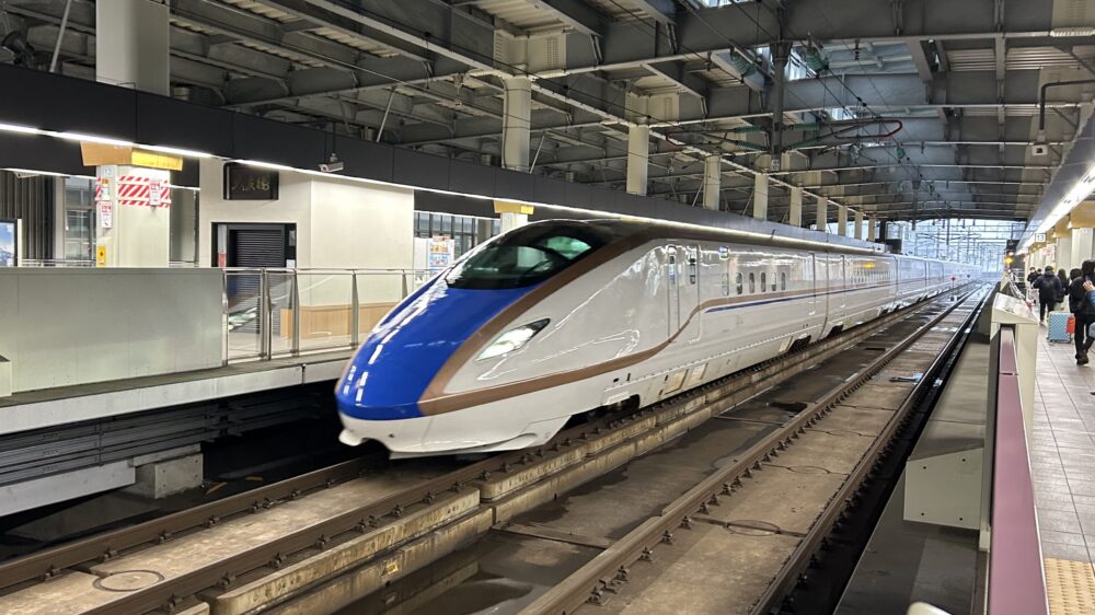 駅ホームに停車する青と銅色のE7系・W7系北陸新幹線